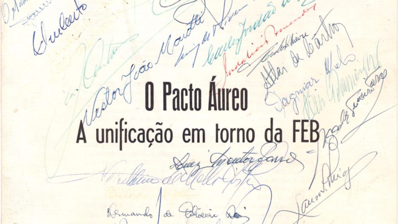 Fotografia de uma página de livro. A página está amarelada com o tempo e nela constam diversas assinaturas feitas à mão, ao centro está uma frase que diz: "O Pacto Áureo — A unificação em torno da FEB".